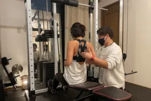 住吉のパーソナルジムで男性パーソナルトレーナーから指導を受けている30代女性